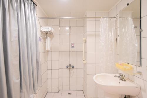 uma casa de banho branca com um chuveiro e um lavatório. em Duke Business Hotel em Zhongli