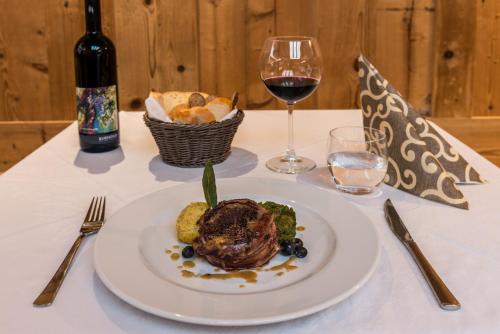 a table with a plate of food and a glass of wine at Hotel Paradiso in Sarnonico