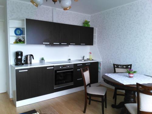 クレサーレにあるGratarre Apartmentのキッチン(黒いキャビネット、テーブル、椅子付)