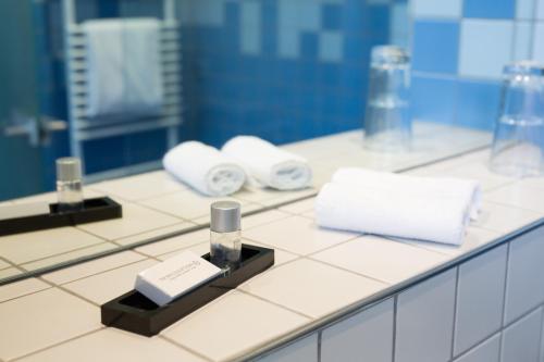 eine Badezimmertheke mit Handtüchern und einer Flasche Parfüm in der Unterkunft Gasthaus Luthemuhle in Nettetal