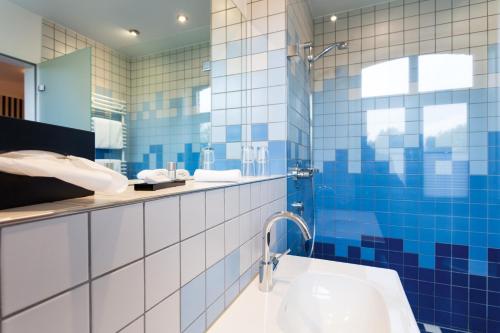 a bathroom with blue and white tiles and a tub at Gasthaus Luthemuhle in Nettetal