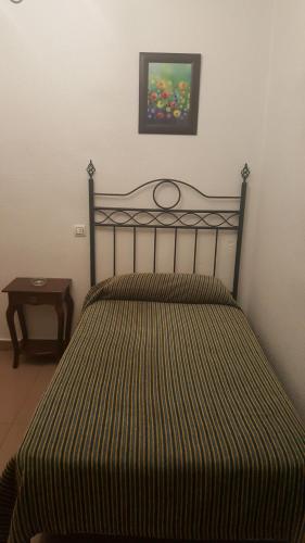 セビリアにあるHostal Trajanoのベッドルーム1室(ストライプのベッドカバー付)