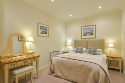 a bedroom with a bed and a dresser and a mirror at Melfort Village in Oban