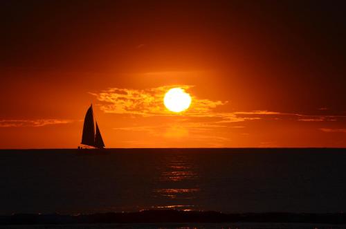 a sail boat in the ocean at sunset at Belle Crique D3 Tamarin Ile Maurice in Tamarin