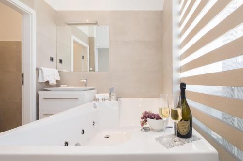a white bathroom with a sink and a bottle of wine at Marina Baotić Apartments in Trogir