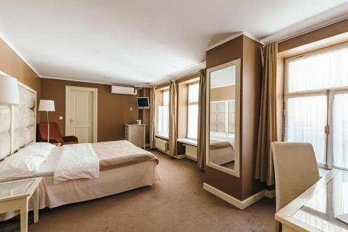 a bedroom with a bed and a desk and windows at Merchants House Hotel in Tallinn