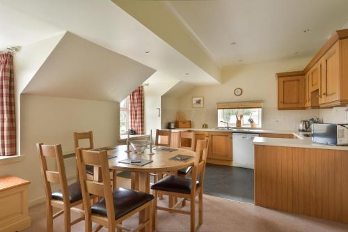 a kitchen with a wooden table and chairs at Melfort Village in Oban