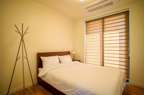 a bedroom with a white bed and a fan at Poema Stay Pension in Jeju