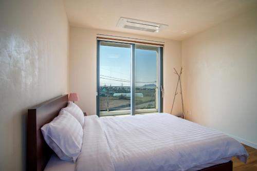 a bedroom with a bed and a large window at Poema Stay Pension in Jeju