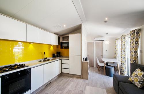 a kitchen with white cabinets and a yellow accent wall at Holiday Marina Resort in Grimaud