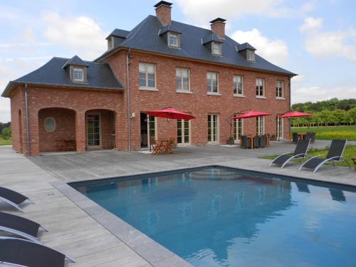 a large brick building with a swimming pool in front of it at Domaine de La Noiseraie in Rhisnes