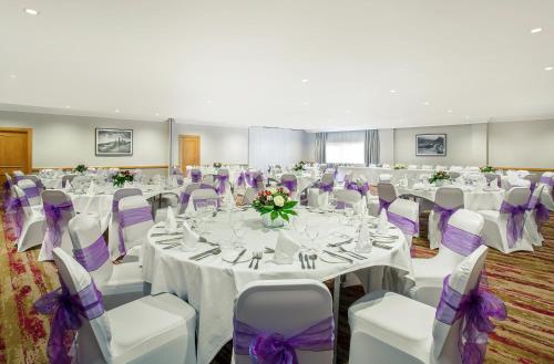 a banquet hall with white tables and purple chairs at Leonardo Hotel Inverness in Inverness