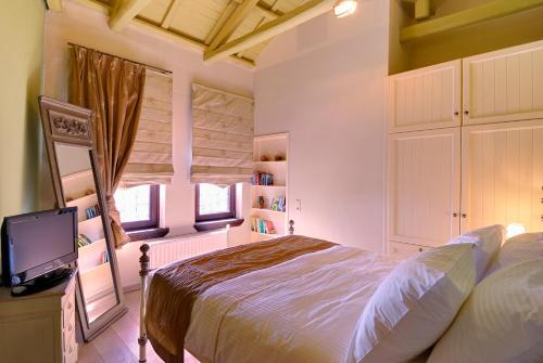 um quarto com uma cama, uma TV e uma janela em Villa Kerasia em Miléai