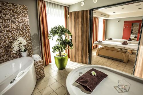 ein Badezimmer mit einer Badewanne und einem großen Spiegel in der Unterkunft Seehotel Fleesensee in Göhren-Lebbin