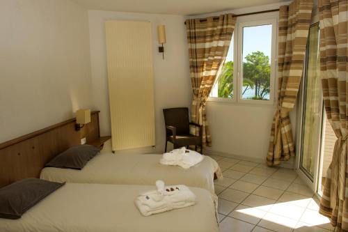 a hotel room with two beds and a window at Le Village des Isles in Taglio-Isolaccio