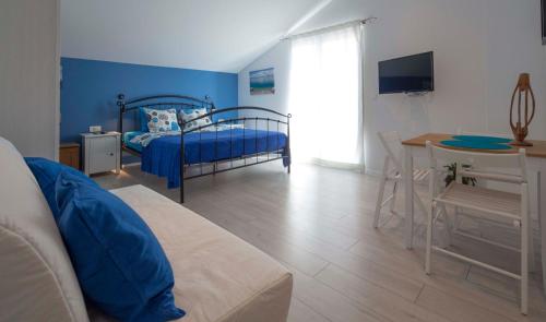 niebieski pokój z łóżkiem, stołem i biurkiem w obiekcie Apartments Denis w Makarskiej