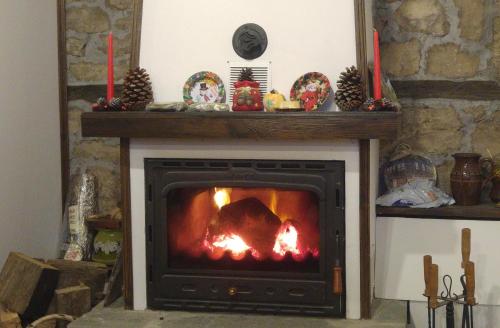 a fireplace with a fire in it with two red candles at Guest House Strumena in Elena