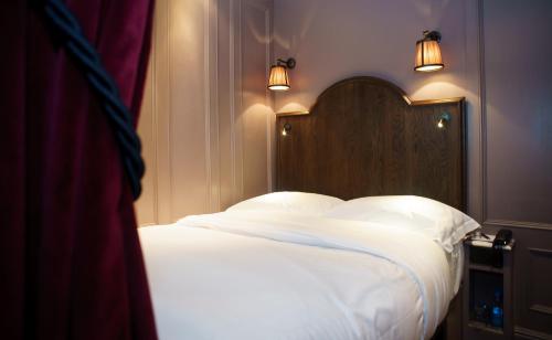 a bed with white sheets and a wooden head board at Mimi's Hotel Soho in London