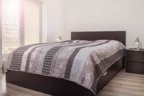 a bedroom with a bed with a black and white blanket at Garden apartments in Prešov