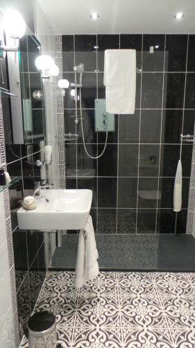 a black and white bathroom with a sink and a shower at The Somerville in Torquay