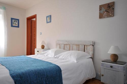 a bedroom with a white bed with a blue blanket at Maison D'hôtes Du Landersbach in Sondernach