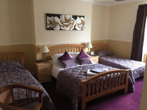 Un dormitorio con dos camas con almohadas moradas. en The Arches Guest House, en Whitby