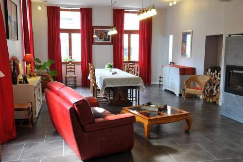 a living room with a red couch and a table at Maison D'hôtes Du Landersbach in Sondernach