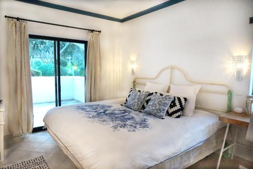 een slaapkamer met een bed met kussens en een raam bij Palmeira VIP Apartment in Portimão