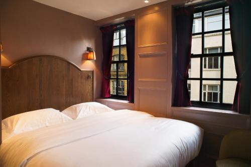 a bedroom with a white bed and two windows at Mimi's Hotel Soho in London