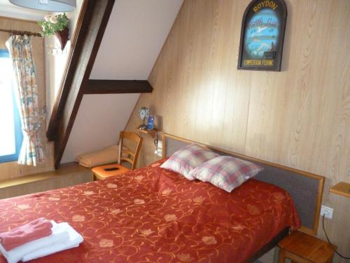 a bedroom with a bed with a red comforter at Auberge des Etangs in Roussent