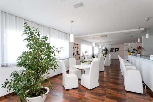 a restaurant with white chairs and tables and plants at Hotel Scialì in Vieste