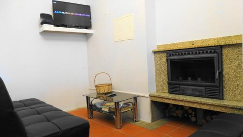 a living room with a fireplace and a tv at Casa do Postigo in Geres