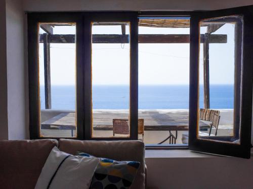 a living room with a view of the ocean through windows at Dammuso sulla scogliera - Pantelleria in Scauri