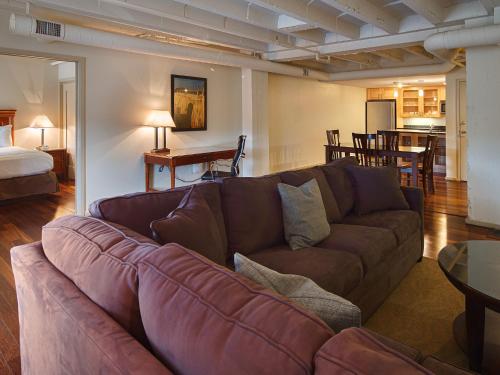 a living room with a brown couch and a bedroom at Grand Eastonian Hotel & Suites in Easton