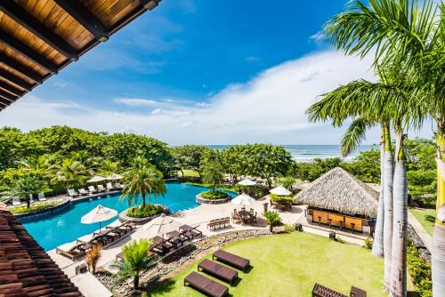 uma vista aérea de um resort com uma piscina e palmeiras em Luxury Vacation Rentals At Hacienda Pinilla em Tamarindo
