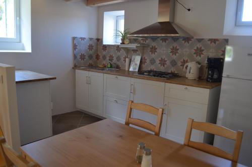 - une cuisine avec des placards blancs, une table et un réfrigérateur dans l'établissement Gîtes La ferme accrochée à la colline, à Lagorce