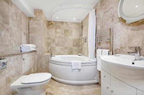 a bathroom with a tub and a toilet and a sink at Queensgate Court in London