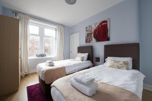 Un dormitorio con dos camas y una ventana. en PREMIER - Crathie View Apartment, en Glasgow