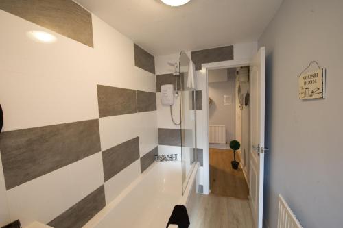 a hallway with a bathroom with a tile wall at PREMIER - Crathie View Apartment in Glasgow