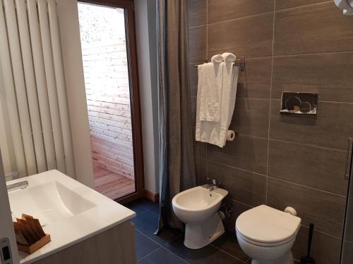 a bathroom with a toilet and a sink and a tub at Aqua Apartments Spa Housemuhlbach in Sappada
