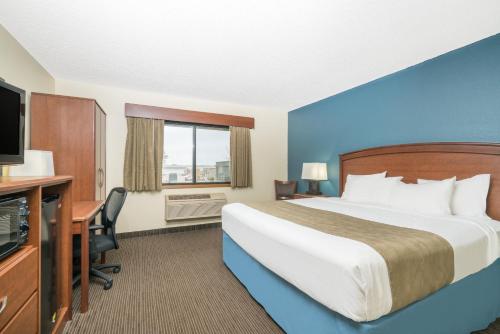 a hotel room with a bed and a desk and a television at Days Inn & Suites by Wyndham Baxter Brainerd Area in Baxter