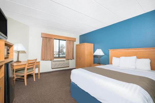 a hotel room with a large bed and a desk at Days Inn & Suites by Wyndham Baxter Brainerd Area in Baxter