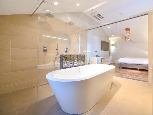 a bathroom with a white tub and a bedroom at Brasserie-Hotel Antje van de Statie in Weert