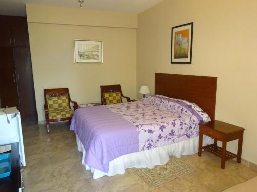 a bedroom with a large bed and two chairs at Hosteria Palmetto in Playas