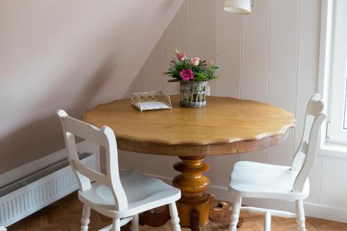 einen Holztisch mit zwei Stühlen und eine Vase mit Blumen darauf in der Unterkunft Bij de Buren in Enkhuizen