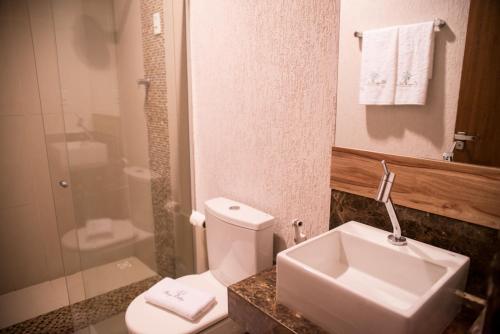 a bathroom with a toilet and a sink and a shower at Village Hotel Pousada in Guamaré