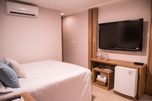 a bedroom with a bed and a flat screen tv at Village Hotel Pousada in Guamaré