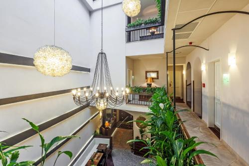 an indoor hallway with potted plants and chandeliers at Hotel Residence Agnes in Prague