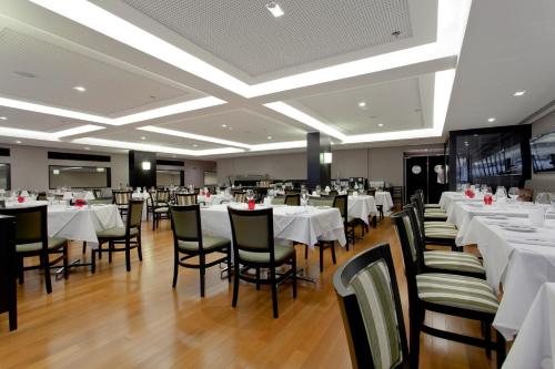 a dining room with white tables and chairs at Golden Tulip São José dos Campos in São José dos Campos