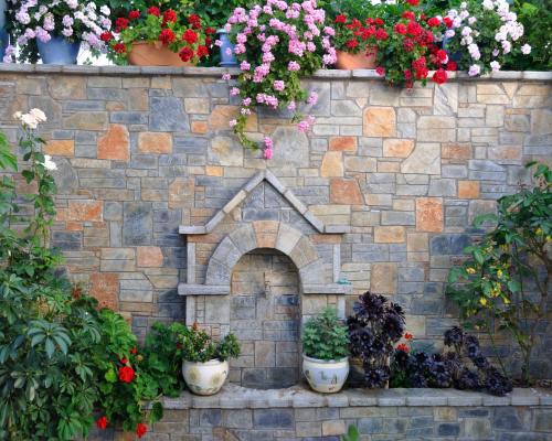a stone wall with potted plants and flowers at Ilias Studios in Patitiri